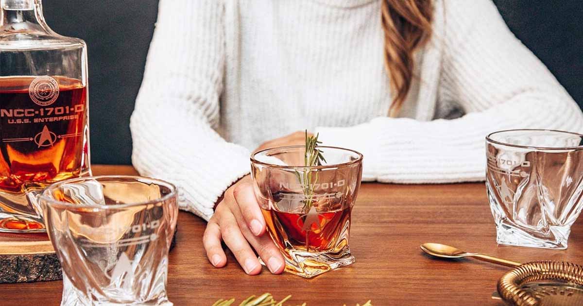 A woman having a rosemary old fashioned in the Star Trek Whiskey Decanter set.