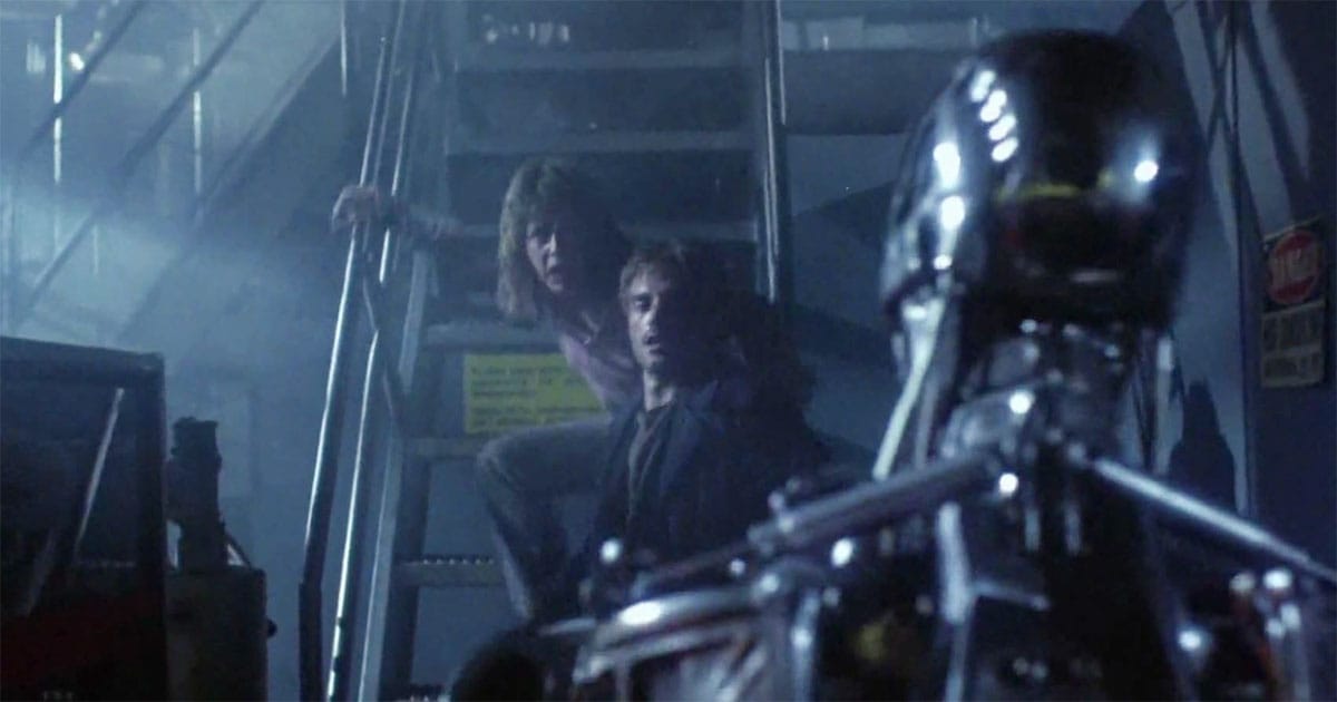 A screen capture of the Terminator in the factory. Reese is still protecting Sarah.