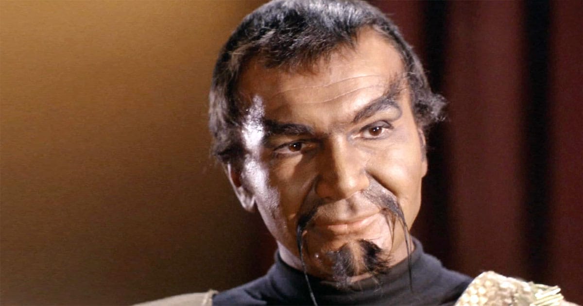 John Colicos as Kor in "Errand of Mercy," wearing a Klingon uniform, smirking with confidence and authority.