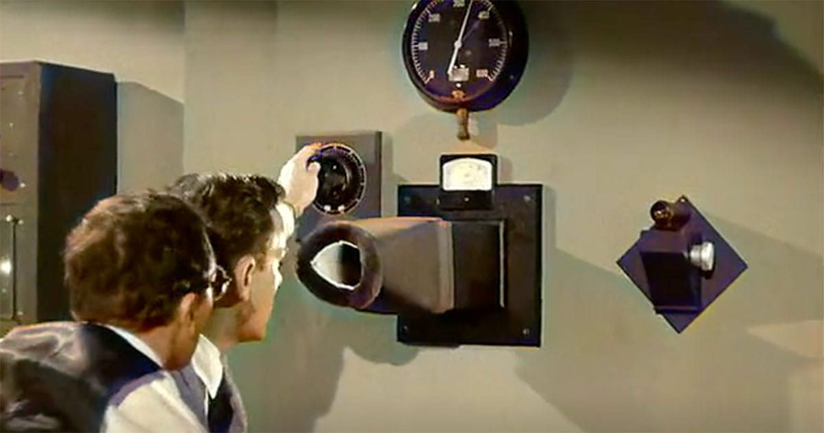 Two scientists in lab coats examine a control panel, adjusting dials and monitoring readings. 