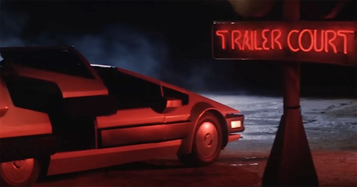 The Starcar from The Last Starfighter parked near a neon-lit trailer court sign at night.