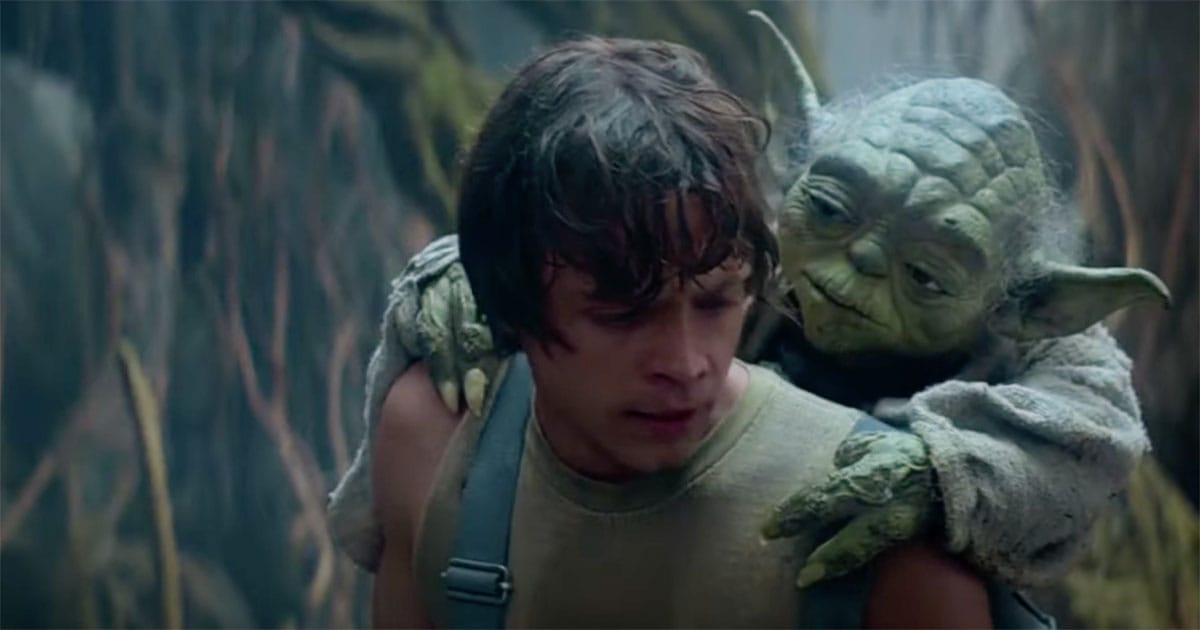 Mark Hamill as Luke Skywalker caring Yoda on his back. In the movie Star Wars a New Hope.