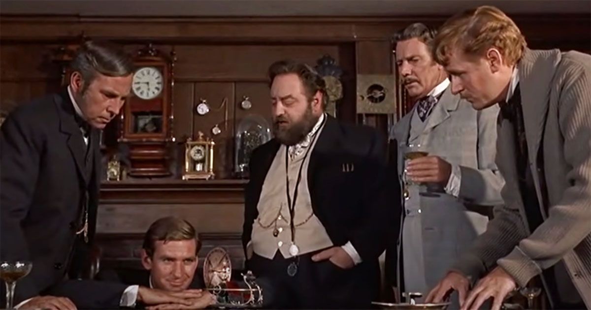 An image from the movie The Time Machine (1860) with 5 gentle men looking at a miniature time machine.