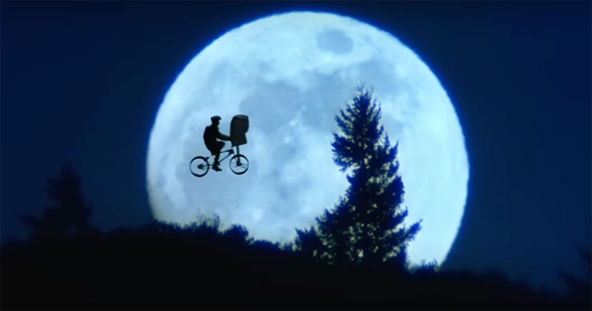 Image from the movie E.T. the Extra Terrestrial of the Elliot(the boy) and E.T. flying through the sunset.